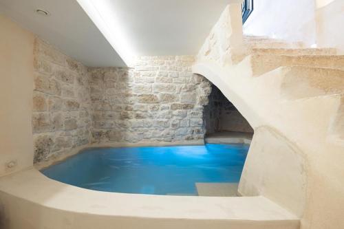 奥斯图尼Suite Le Grotte的石墙客房内的大蓝色浴缸