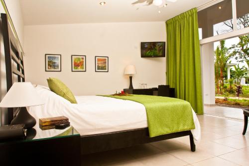 博卡奇卡滨海博卡斯酒店的一间卧室配有床和绿帘