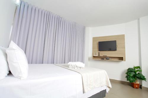 戈亚尼亚Apartamento 1009的卧室配有白色的床和电视