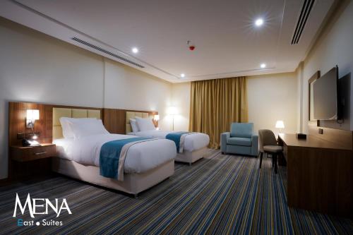 达曼Mena East Suites Dammam的酒店客房设有两张床、一张桌子和一台电视。