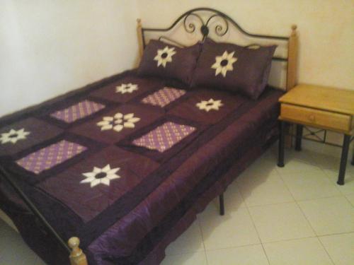卡萨布兰卡Appartement Aznavour的一张带紫色毯子的床,上面有白色的花朵