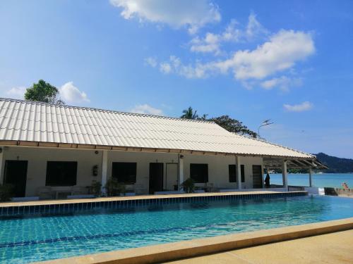 通奈潘海滩Thong Nai Pan Beach Resort的一座位于一座建筑前方的游泳池,背景是大海