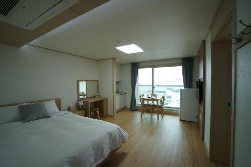 济州市The Beach Pension的一间卧室配有一张床、一张桌子和一个窗户。