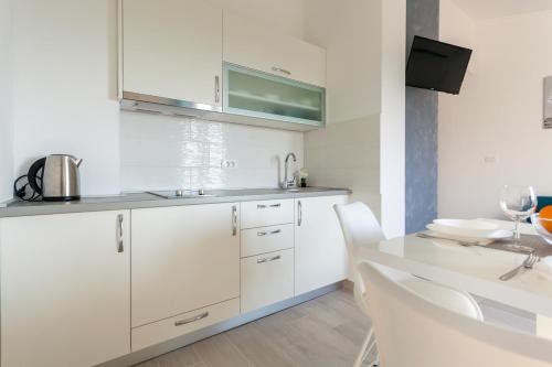 奥米沙利Apartments Didi的厨房配有白色橱柜和桌椅