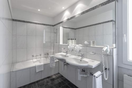阿罗萨Blatter's Arosa Hotel & Bella Vista SPA的白色的浴室设有水槽和浴缸。