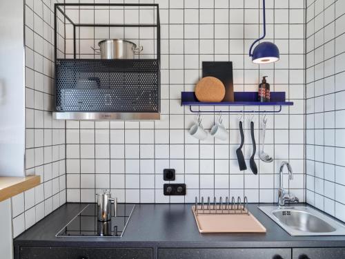 沃尔夫斯堡STAYERY Wolfsburg City的厨房设有水槽和白色瓷砖墙壁。
