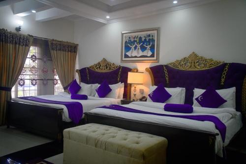 拉合尔Premier Inn Grand Gulberg Lahore的一间卧室配有两张带紫色枕头的床和一张沙发