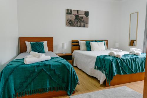 大里贝拉Village House的一间卧室配有两张带绿色床单和毛巾的床。