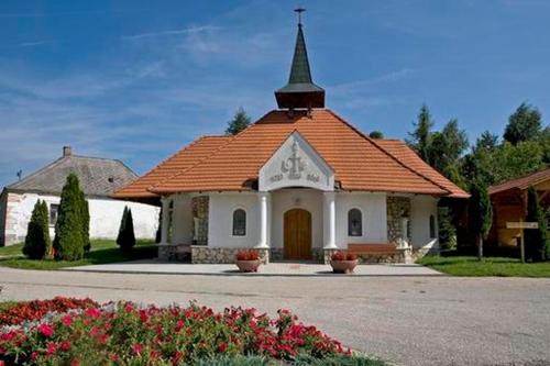 NémetbányaHarmónia Vendégház的一座带橙色屋顶和陡峭壁的小教堂
