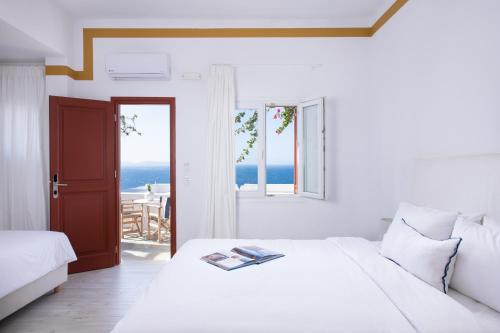 米克诺斯城塔古酒店的一间白色的卧室,配有一张床,享有海景