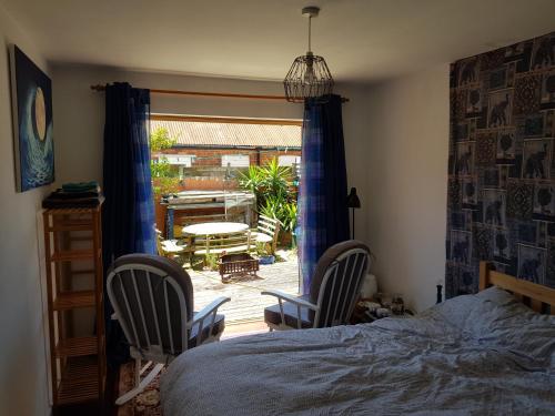 埃克斯茅斯Garden room的一间卧室配有一张床和两把椅子,还有一个庭院