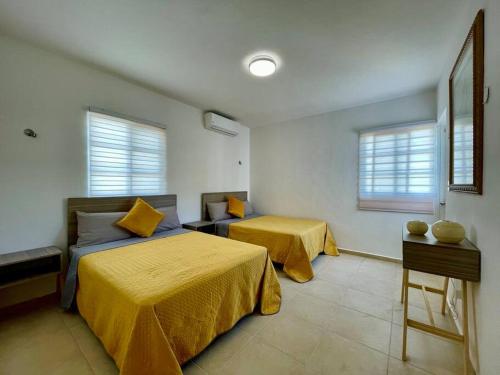 坎昆Casa Mar y Amor的一间卧室设有两张带黄色床单和窗户的床。
