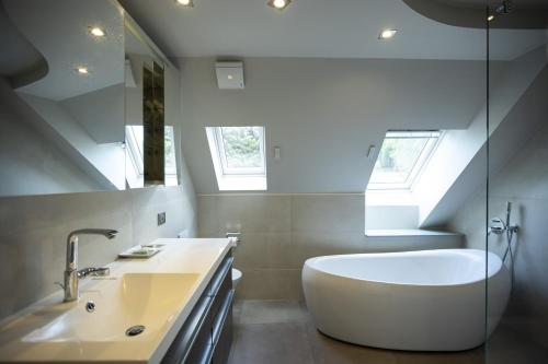 拉普特鲁瓦Hôtel Restaurant Les Alisiers的浴室配有白色浴缸和水槽