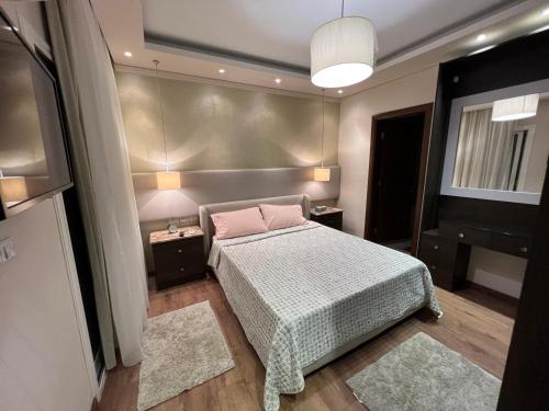 Burg el-ḤudûdFamilies Only - Rehab 2 - Two Bedrooms Flat for you的一间卧室配有床、两张桌子和一台电视