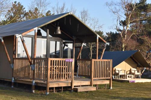 卡兰茨奥赫Safari Lodge, glamping aan zee!的黑色屋顶和门廊的房子