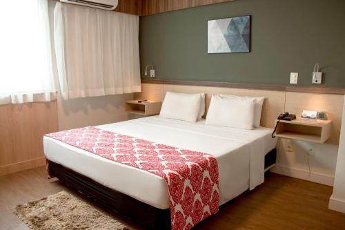 坎普斯戈伊塔卡济斯坎波斯多斯戈塔卡兹舒适酒店的卧室配有一张大白色床和红色毯子