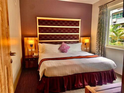 坎帕拉Arcadia Suites - Kampala的一间卧室设有一张大床和一个窗户。
