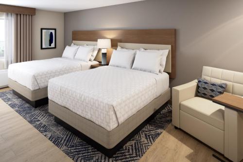 奥本希尔斯Candlewood Suites - Detroit - Auburn Hills, an IHG Hotel的酒店客房,配有两张床和椅子