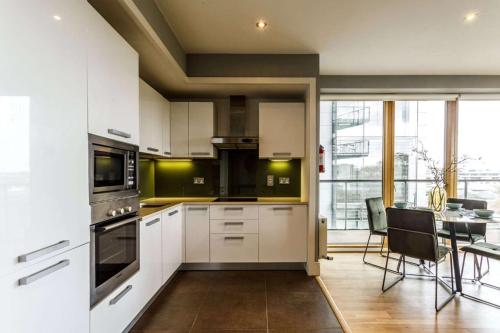 都柏林Private Room Available in Spacious High Rise Apartment with Park & City View的厨房配有白色橱柜和桌椅