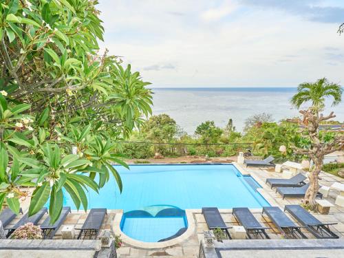 艾湄湾Anda Amed Villas & Spa的一个带椅子的游泳池,背景是大海
