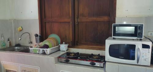 班武里府SeeSea Thai wooden house on beachfront的厨房配有微波炉、炉灶和水槽。