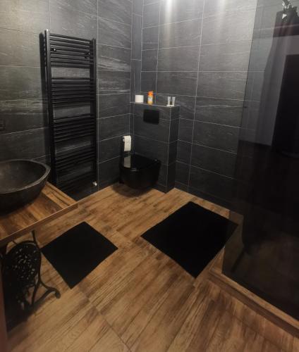 萨图马雷La teatroom的浴室铺有黑色的地板,配有浴缸。