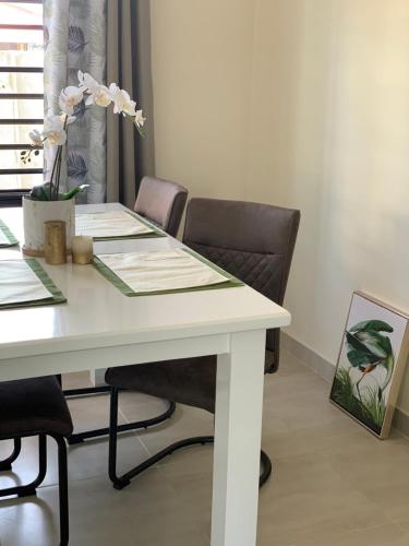 帕拉马里博Casa Alta Gracia的一张带椅子的白色桌子和一张带鲜花的桌子