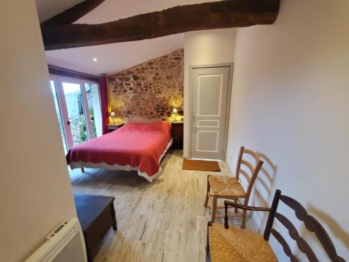 La Pommeraie-sur-SèvreGites De La Brunière的一间卧室配有红色的床和桌椅