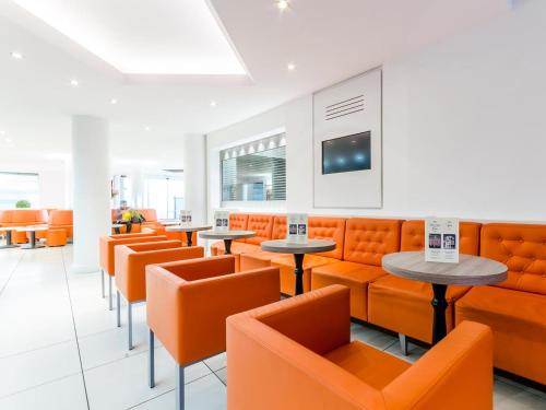 卢尔德阿吉纳酒店的一间设有橙色椅子和桌子的餐厅
