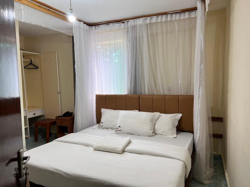 TsavoLavender Garden Hotel的卧室内的一张带白色床单和枕头的床