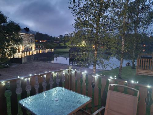 Warton4 Bed Luxury Lodge with Hot tub near Lake District的天井配有桌子和带灯的围栏。
