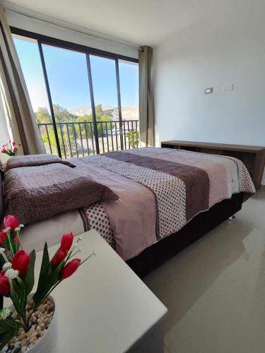 卡马纳Departamentos en Camaná的一间卧室配有一张床和一张鲜花桌子