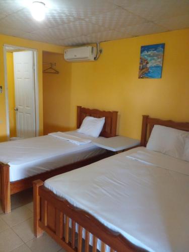 PedregalCabañas Martina Surf Playa Guanico的黄色墙壁客房的两张床