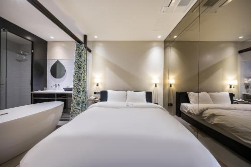 首尔Hotel Lemong的一间卧室设有两张床、一个浴缸和一个水槽