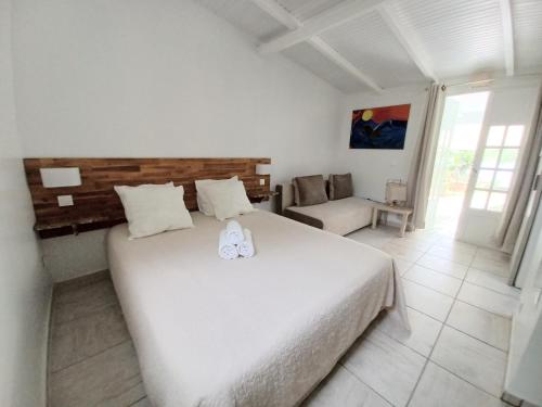 卡佩斯特La Rose du Bresil Marie-Galante的卧室配有一张白色的大床和一张沙发。