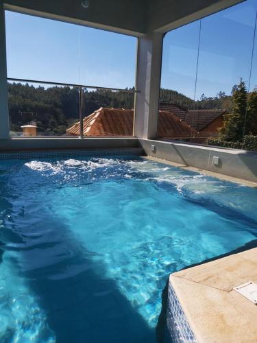 蒙特韦尔迪Pousada Winterhaus的一座蓝色海水大型游泳池,设有大窗户