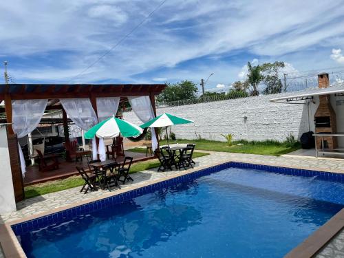 新艾朗Casa Boto Tucuxi 2的房屋旁的游泳池配有椅子和遮阳伞