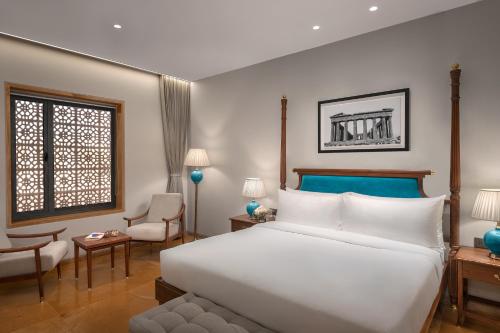 普杰Time Square Resort & Spa Bhuj的卧室配有一张白色大床和一把椅子