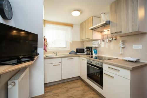 博希尼Apartment Žvan的一间小厨房,配有白色的橱柜和一台电视