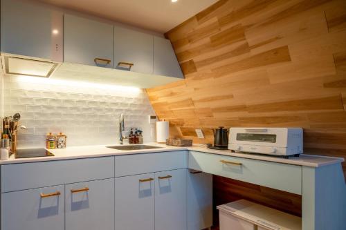 轻井泽A-Frame House Minami Karuizawa - Vacation STAY 58046v的厨房配有白色橱柜和木墙