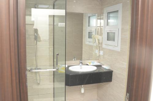 马斯喀特Asfar Hotel Apartments的一间带水槽和玻璃淋浴的浴室