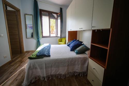 马戈马达斯Affittacamere Oasi di Padru B&B的一间卧室配有一张带蓝色枕头的床和一扇窗户。