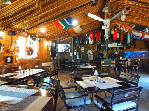 上瓦特法尔Aloes Country Inn的餐厅设有木桌、椅子和电视。