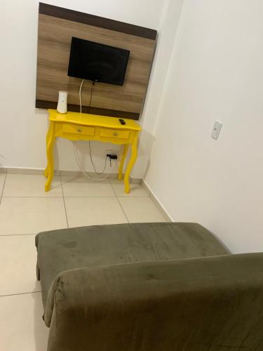帕罗卡Ocean Residence的客房设有一张桌子、一台电视和一张黄色的桌子。