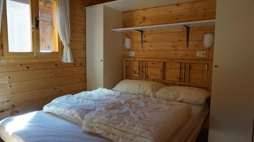 波尔莱扎Vakantiehuis Porlezza的卧室内的一张床铺,设有木墙
