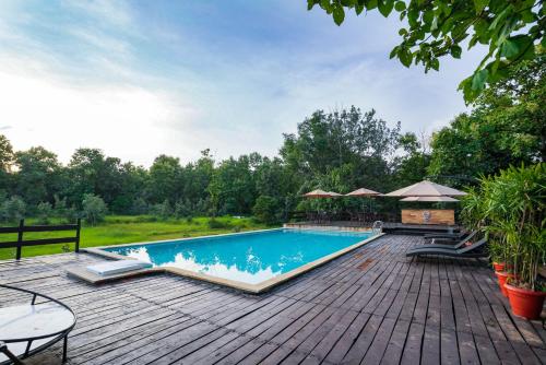 KhawāsaLA SELVA Resort, Pench National Park的一个带木制甲板的庭院内的游泳池