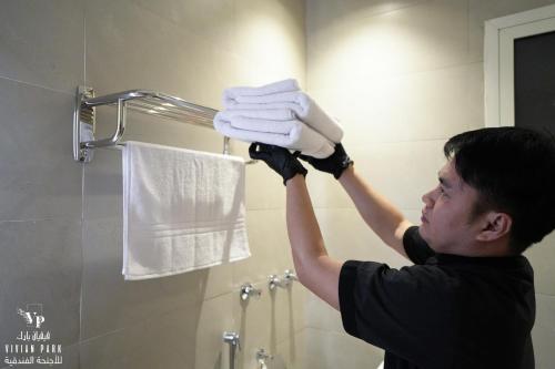 利雅德Vivian Park Residential Apartment的把一堆毛巾放在浴室里的男人