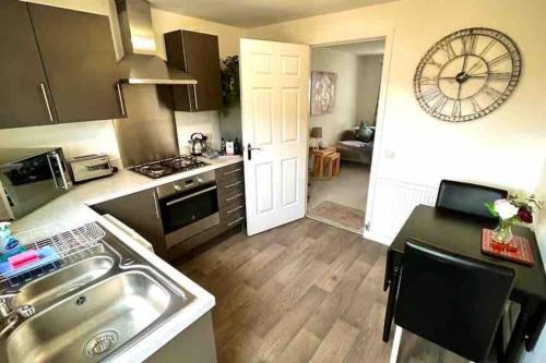 金罗斯Loch Leven Getaway - 2 bed house的厨房配有水槽和墙上的时钟