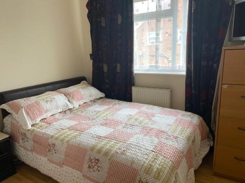 NortholtSpecious Room in Northolt的一间卧室配有一张带被子的床和一扇窗户