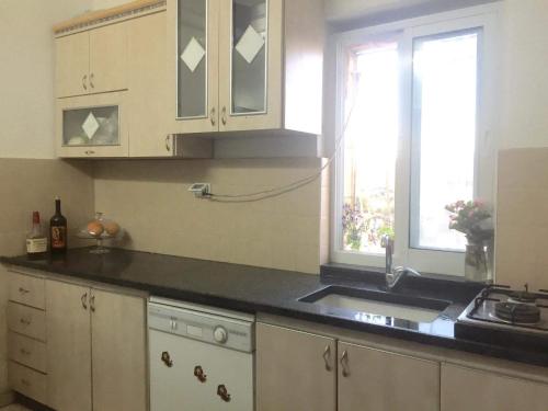 伯利恒Bayt Ateeq (Ateeq's house)的厨房配有白色橱柜、水槽和窗户。